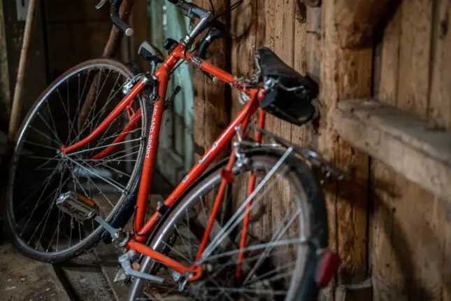 a red bike leaning against a wooden wall