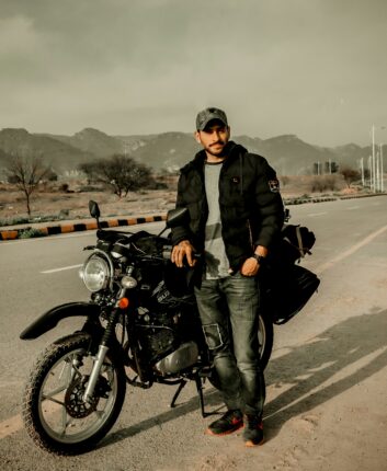 a man standing next to a motorcycle on a road